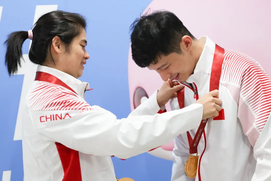 黄梦萍(左)在后台为罗振邦戴上金牌。